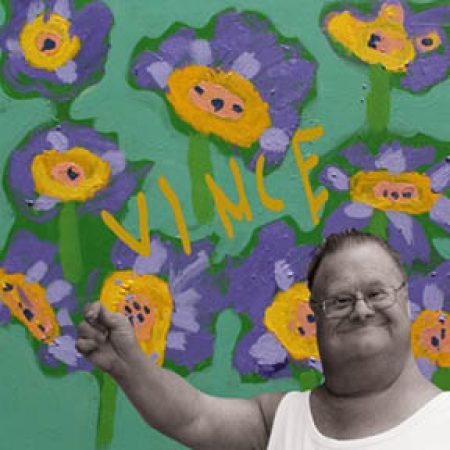 Vince smiling with background his painted flowers and signature