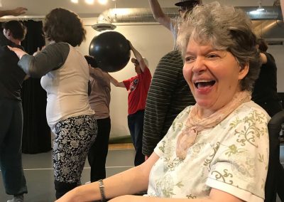 Laughing woman with wheelchair, dance class in background