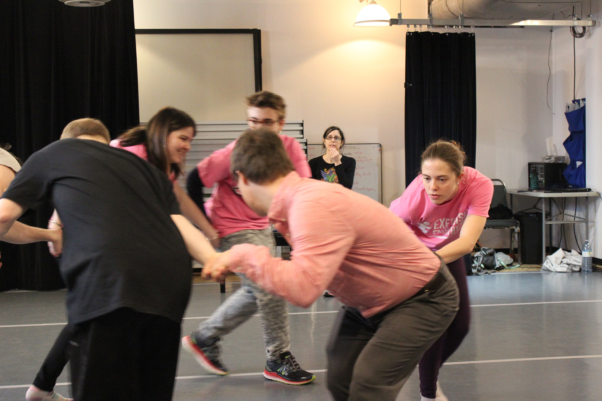 Dance group circles, choreographer watching