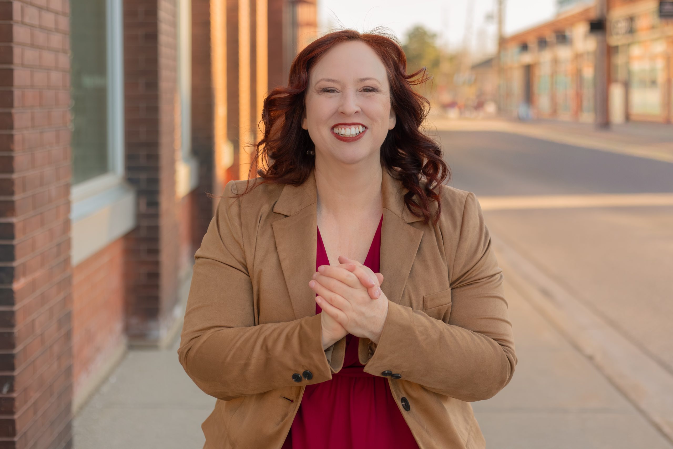 Incoming Executive Director Nicole Fougère standing outdoors on a street, smiling with hands clasped.